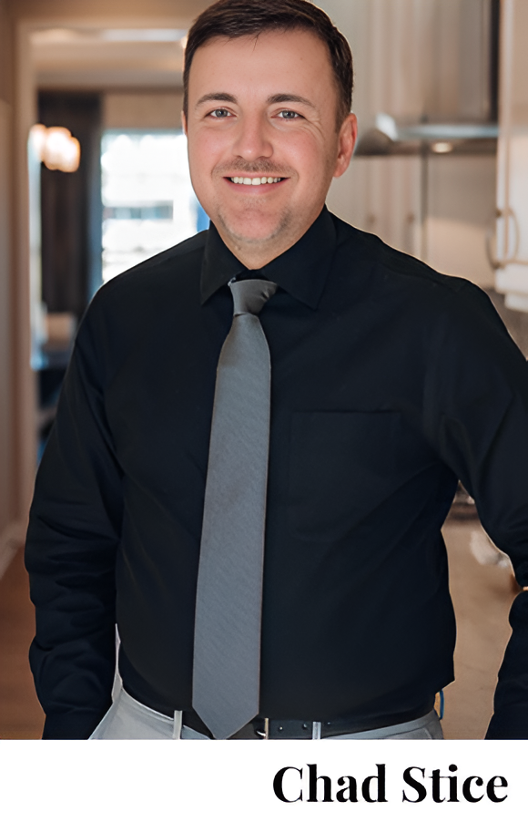 Man in a black shirt and gray tie smiling indoors.